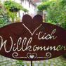 Metal sign with the inscription 'Welcome' in a garden.