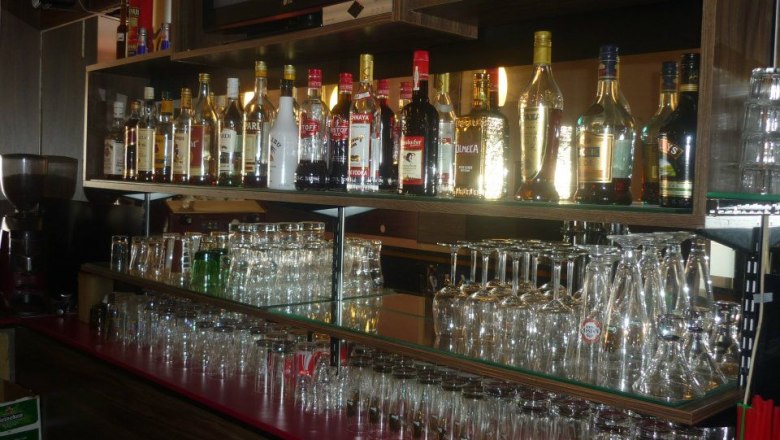 Shelf with bottles and glasses in a bar.
