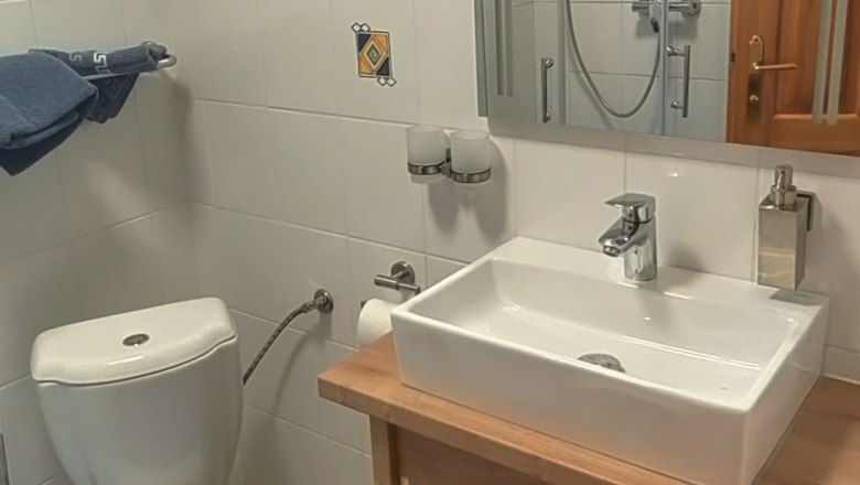 Small bathroom with toilet, washbasin and mirror.