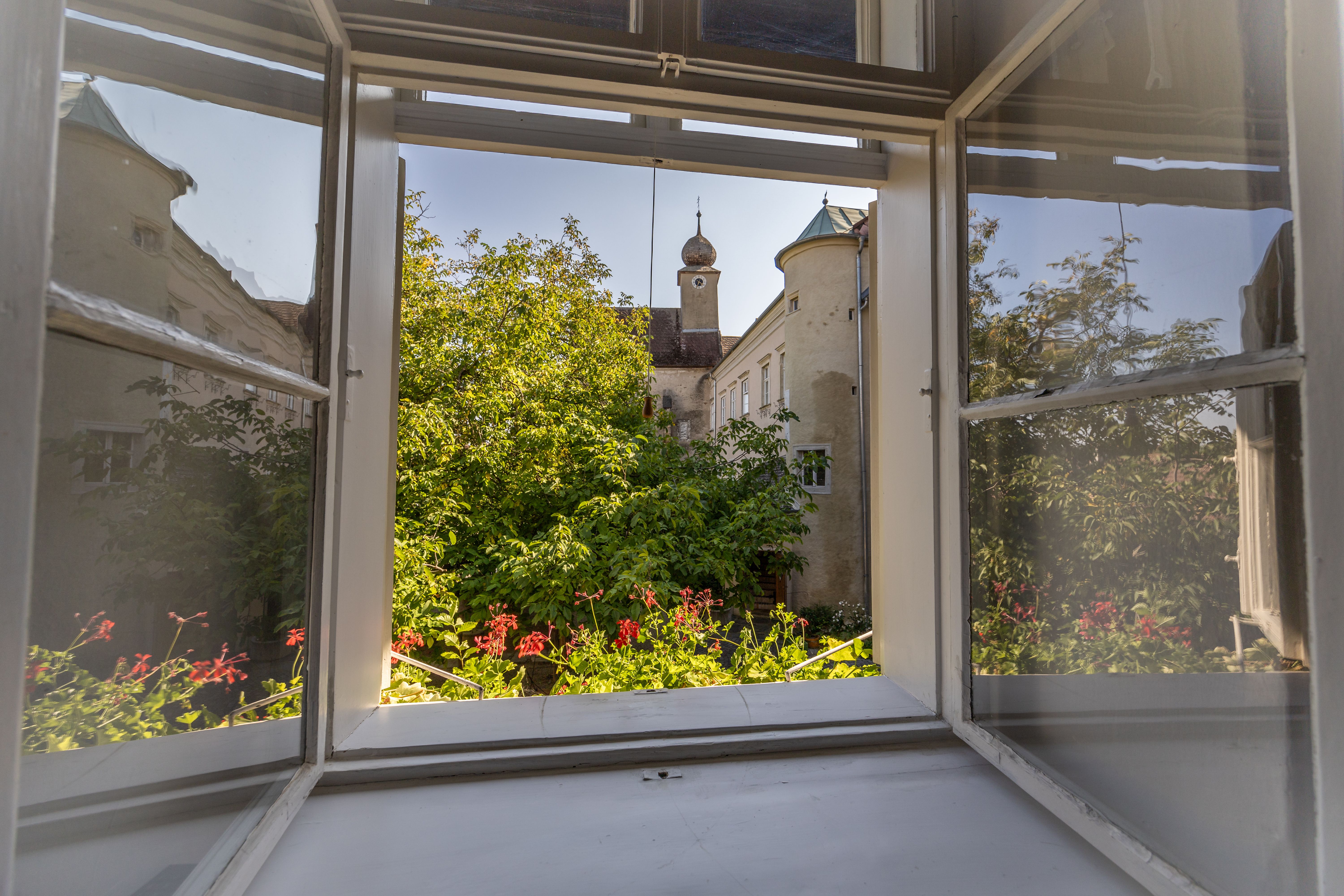 Bedroom with vaulted ceiling, wooden floor, bed, armchair, chest of drawers and fur rug.