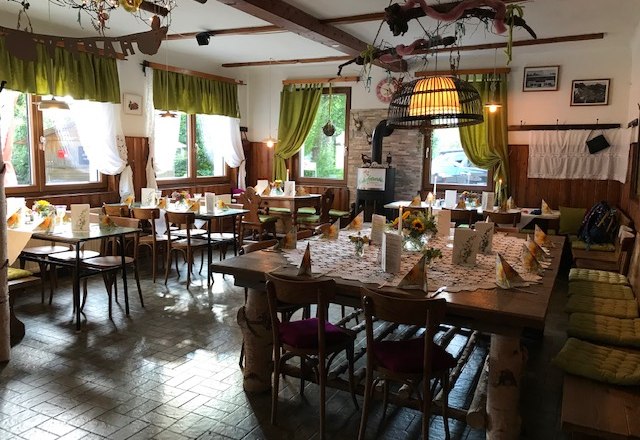 Cozy dining room with wooden furniture, decorated with flowers and tablecloths.