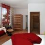 Modern guest room with red sofa, green-red bed and large window.