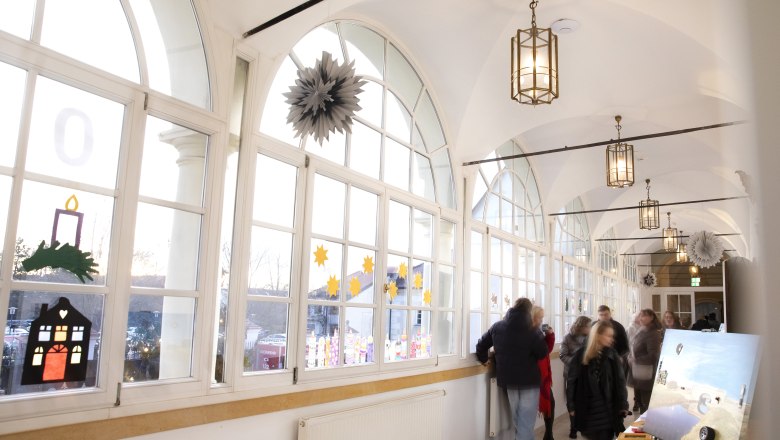 A bright corridor in the castle with large windows and a stall at the Christmas market with art.