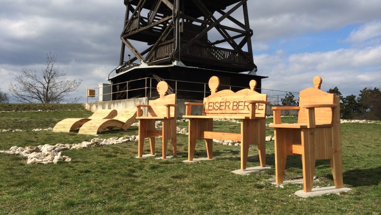Wooden chairs and loungers in front of an outdoor viewing tower.