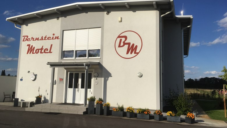 Exterior view of the Bernstein Motel with flowers and blue sky.