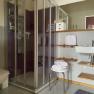 Modern bathroom with shower, washbasin, towels and shelves.