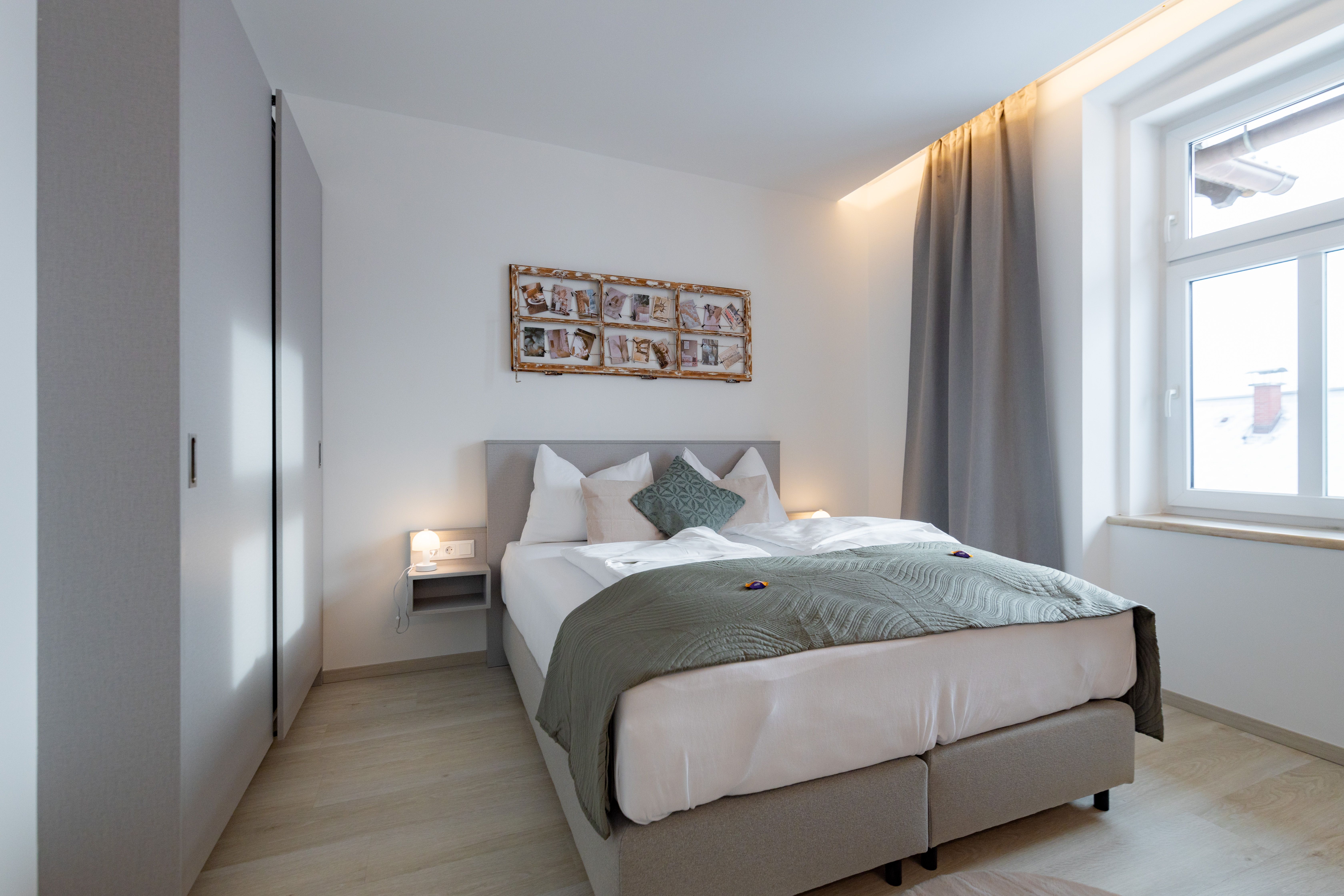 Modern bedroom with double bed, gray curtains and wall decoration.