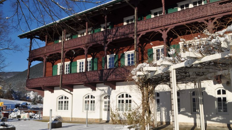 A traditional building with wooden decorations in winter, surrounded by snow and blue skies.