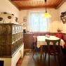 Cozy kitchen with tiled stove, wooden table and corner bench.