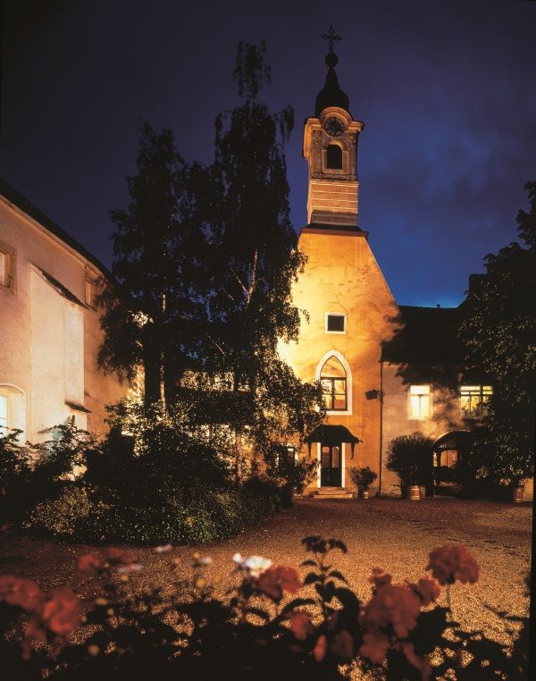 Illuminated building at night with tower and trees in the foreground.