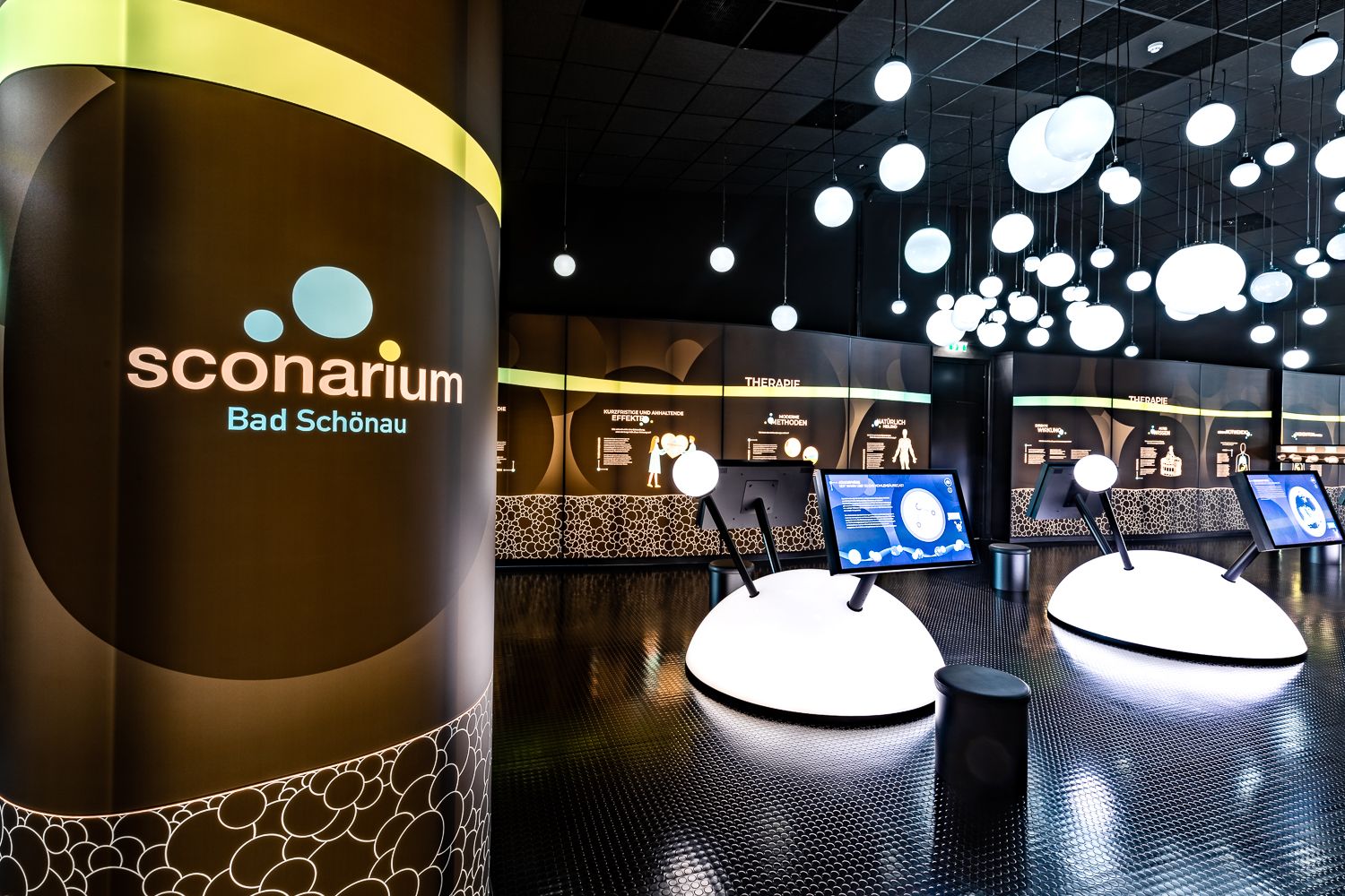 Interior view of the Sconarium exhibition in Bad Schönau with interactive displays and illuminated spheres on the ceiling.