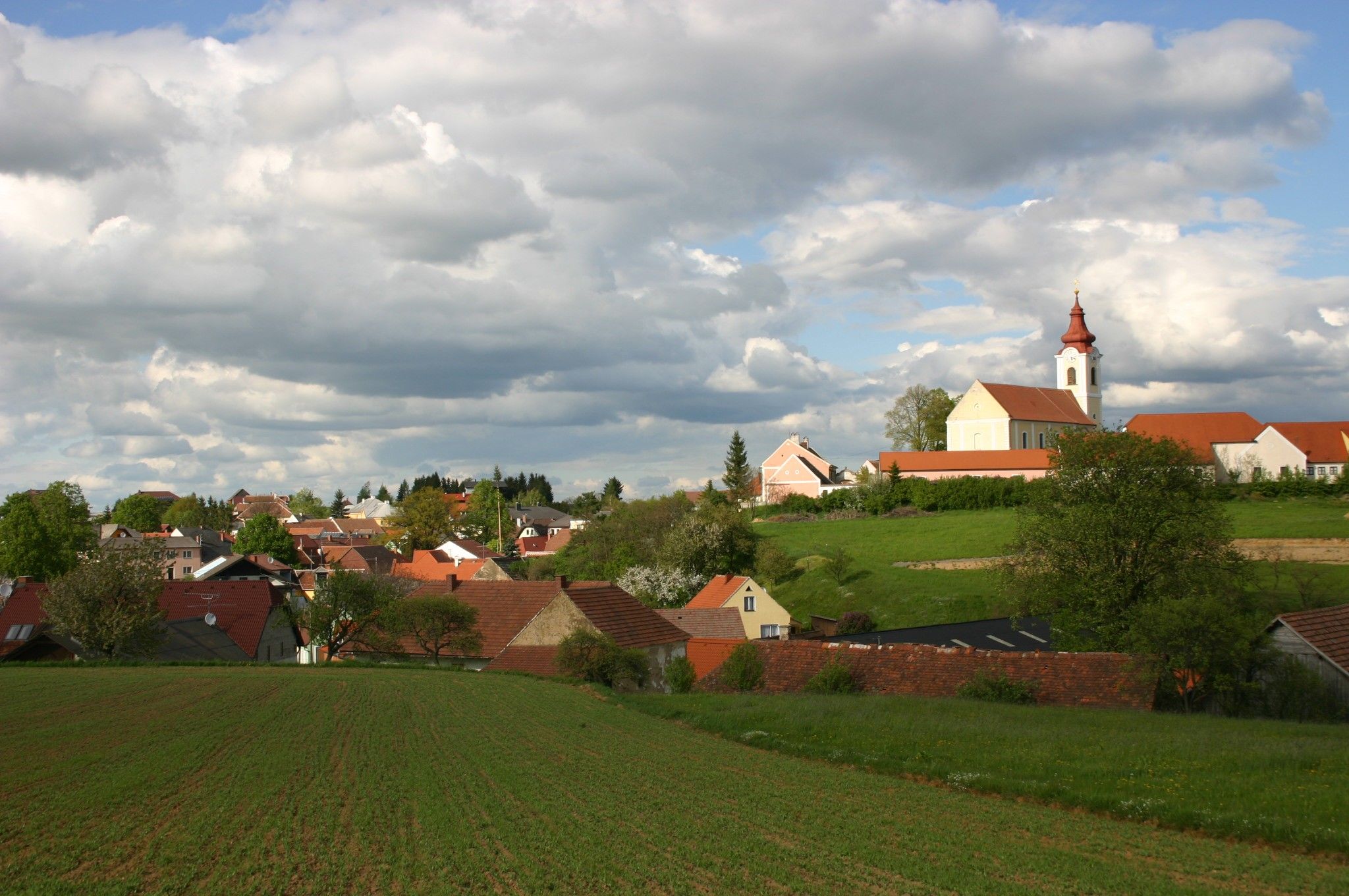 Landscape with village and church under a cloudy sky.