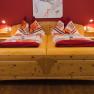 Comfortable double bed with red wall and wooden floor.
