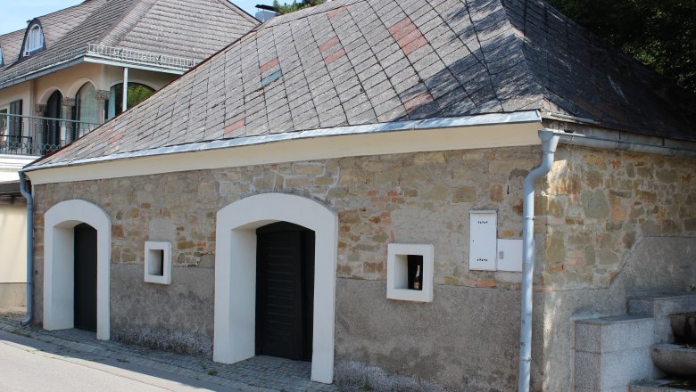 A traditional building with a stone wall and slate roof in Langenzersdorf.