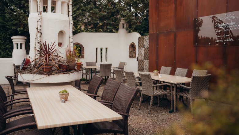 A cozy guest garden with wooden tables, woven chairs and decorative plants in a white tower.
