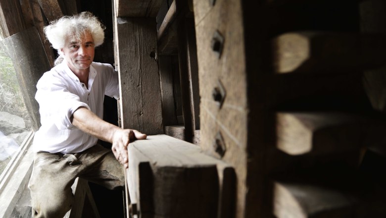 A man with white hair in an old wooden mill.