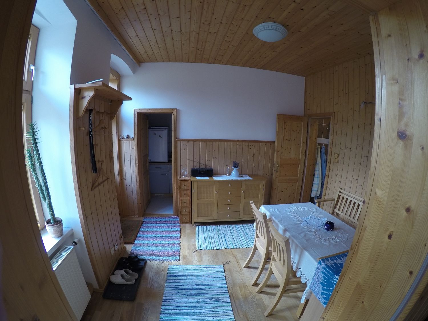 Dining room in a vacation apartment with wooden walls, dining table, chairs and carpets.