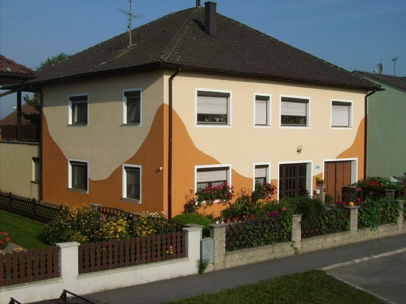 Two-storey house with orange-beige façade and garden.