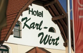 Fa&ccedil;ade of the Hotel Karl-Wirt with red roof and green shutters.