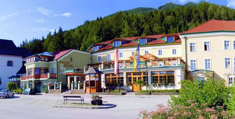 Exterior view of a traditional inn next to a church in a mountainous landscape.