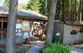 Entrance to a forest tavern with wooden hut and flowers.