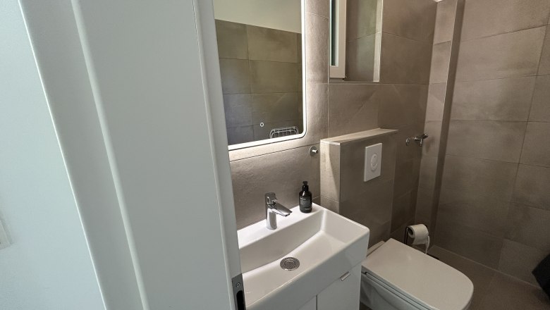 Modern bathroom with washbasin, mirror and toilet.