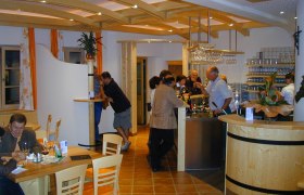 Interior view of a wine tavern with guests at the bar and at tables.