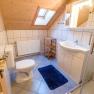 Bathroom with sloping ceiling, washbasin, toilet, shower and blue carpet.