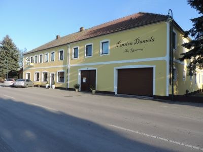 Yellow building with the inscription 'Pension Daniela' on a street.