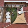 Bird's eye view of the inner courtyard with green lawn, white parasols and guests at a reception.