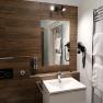 Modern bathroom with wooden paneling, washbasin, mirror, towel rail and hairdryer.