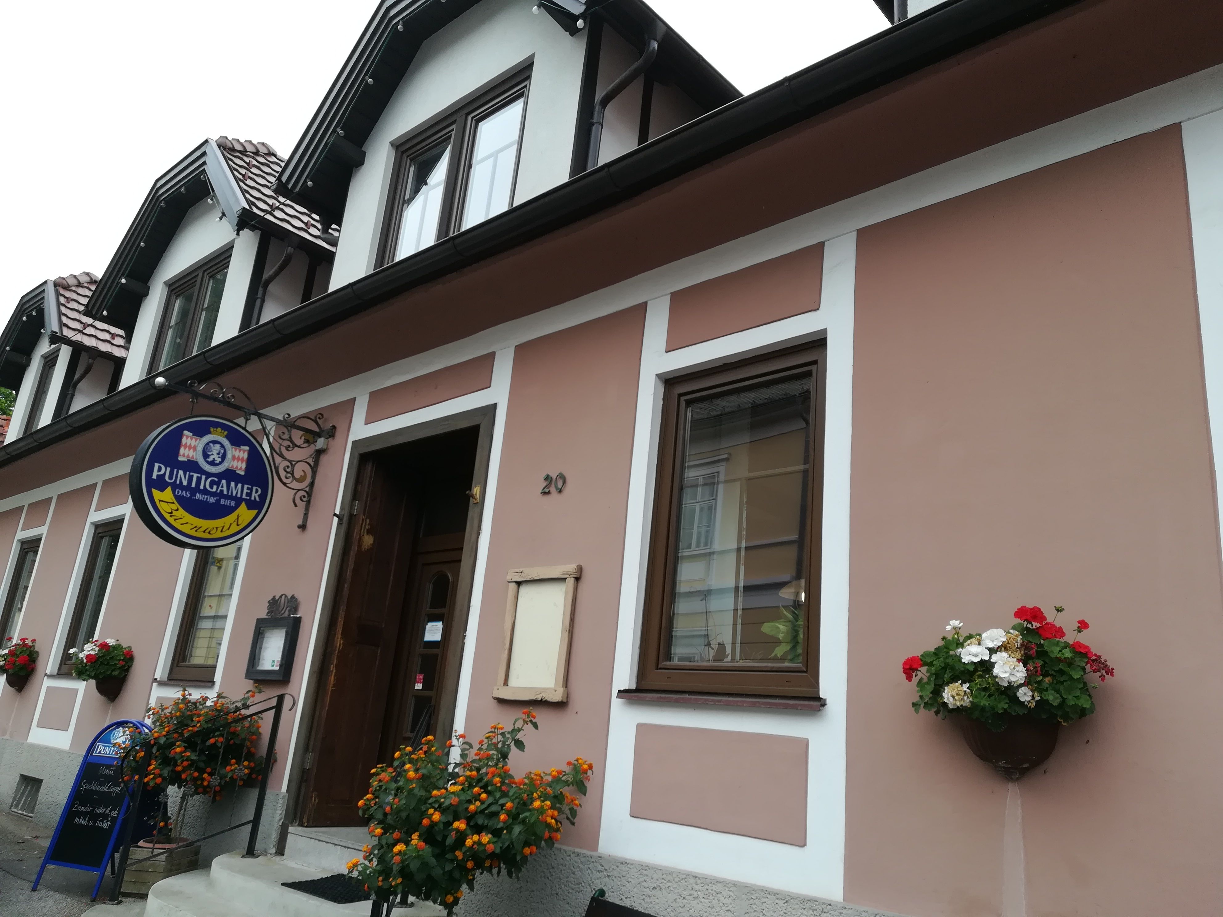 Exterior view of a building with 'Puntigamer' sign and floral decoration.