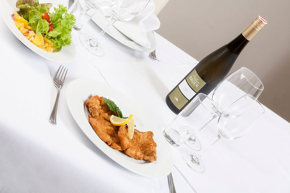 Set table with schnitzel, salad and bottle of wine.