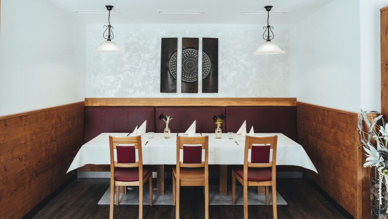 A stylishly laid table in a restaurant with wood paneling and modern art on the wall.