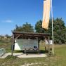 Rest station with covered table, bicycle stand and information boards in a green setting.