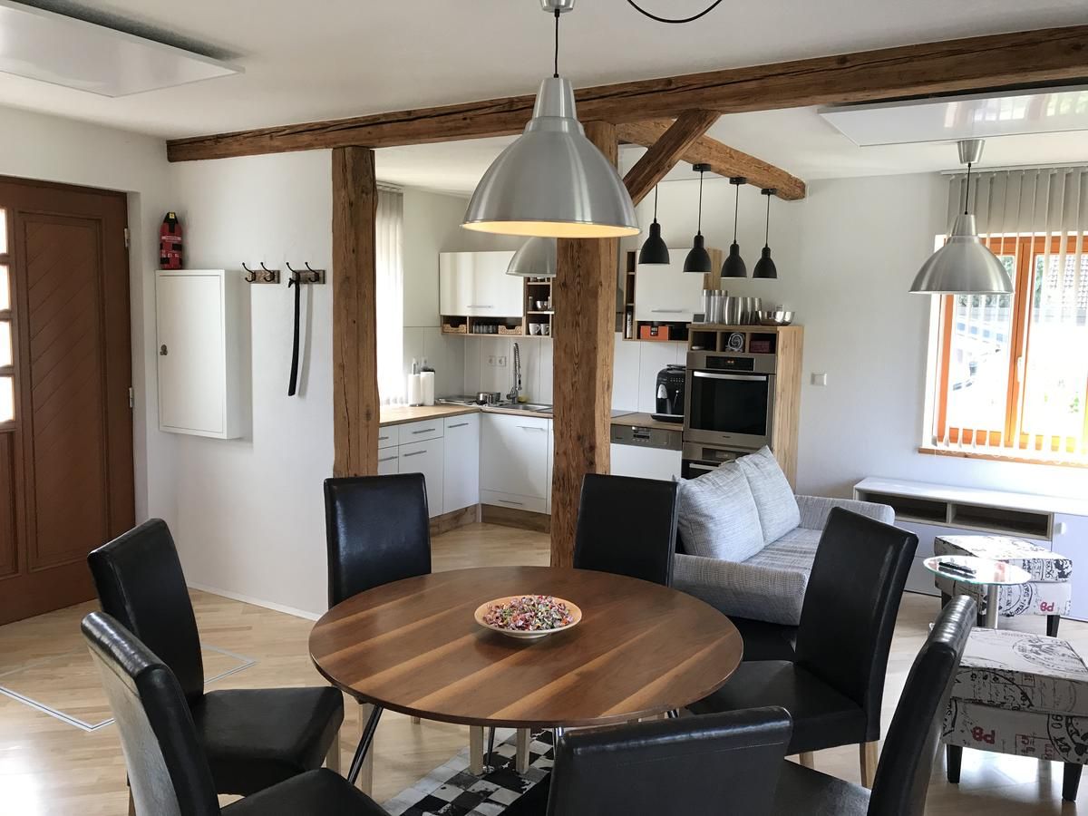 Modern living area with dining table, chairs, kitchen and sofa.