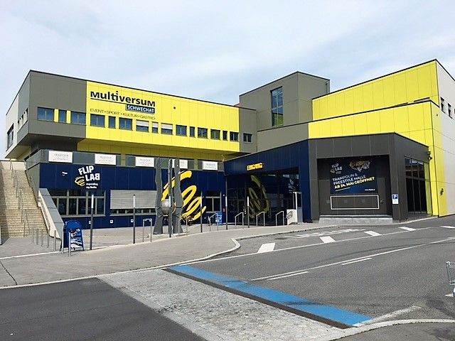 Exterior view of the Multiversum Schwechat, a modern building with yellow and blue facades.
