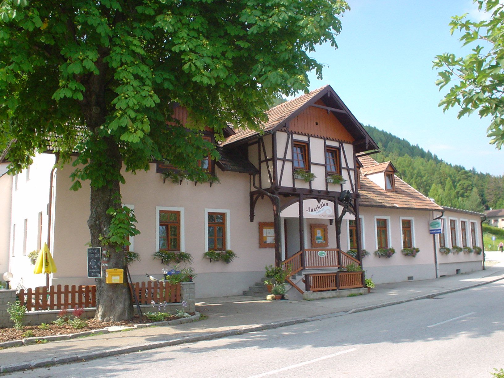 Traditional inn, surrounded by flower boxes and trees.