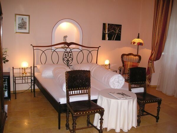 Cozy bedroom with double bed, antique chairs and table lamp.