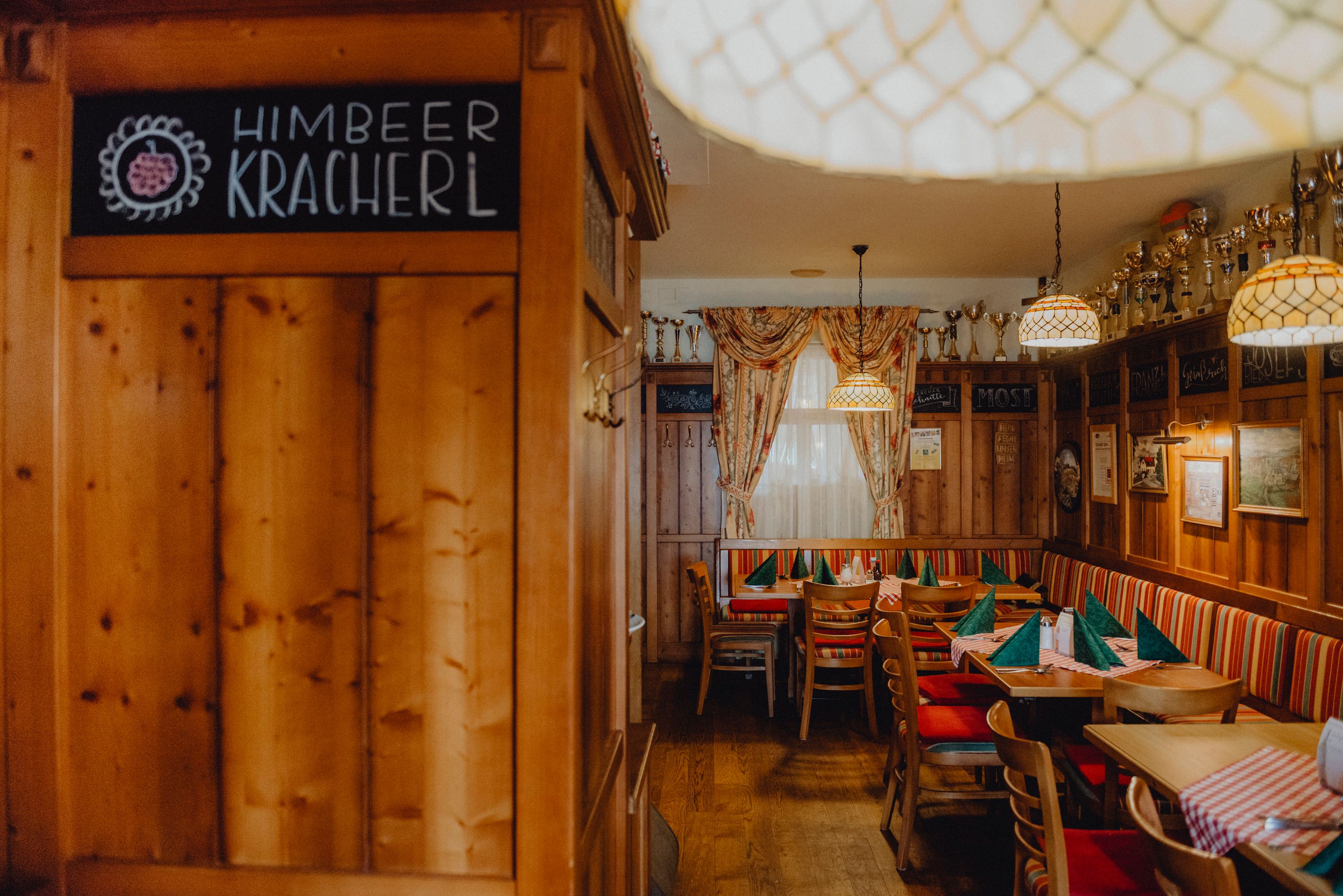 Cozy farmhouse parlor with wooden furniture, checkered tablecloths and goblets on a shelf.