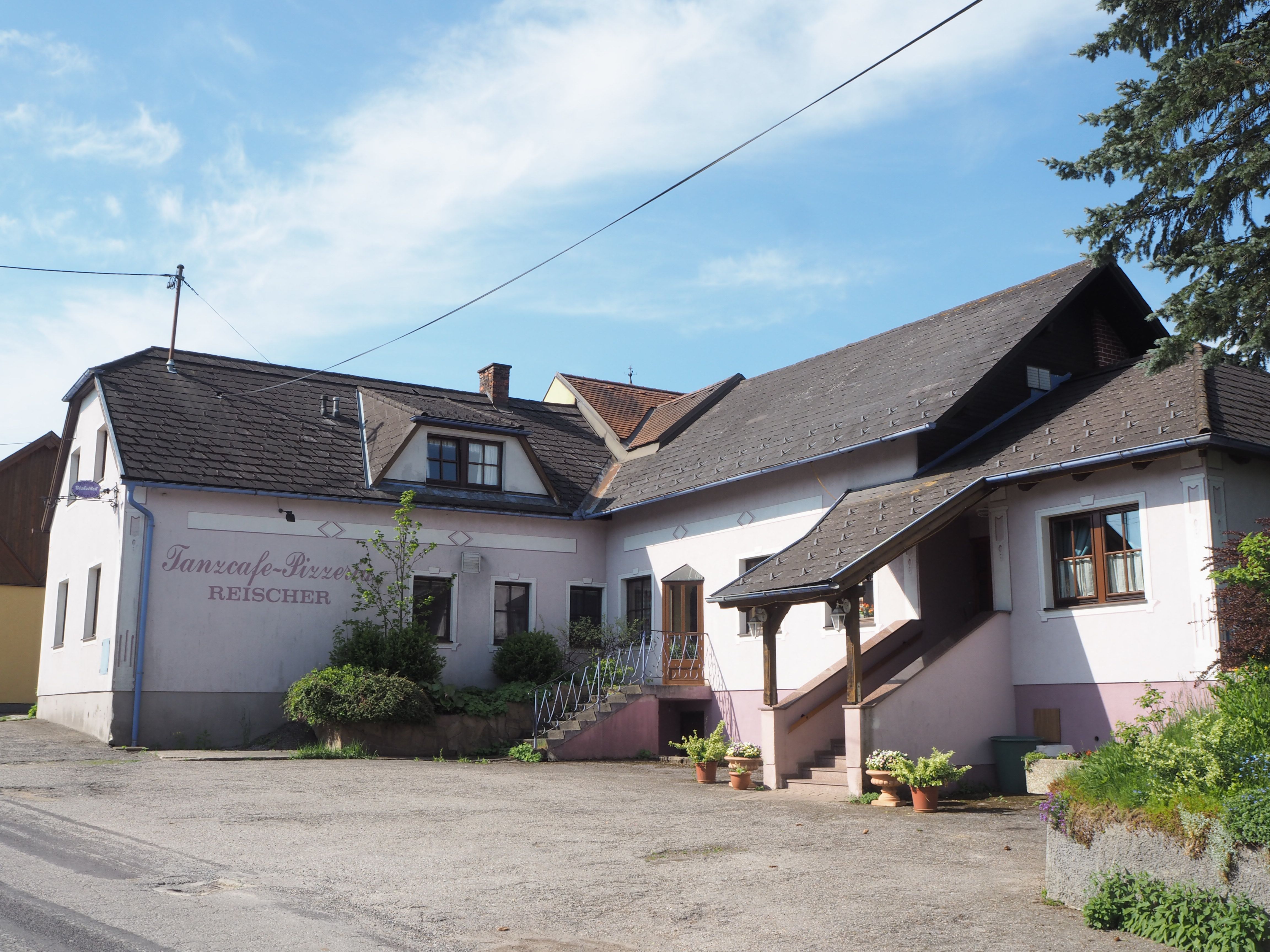 Exterior view of a building with the inscription 'Tanzcafe-Pizzeria Reischer'.