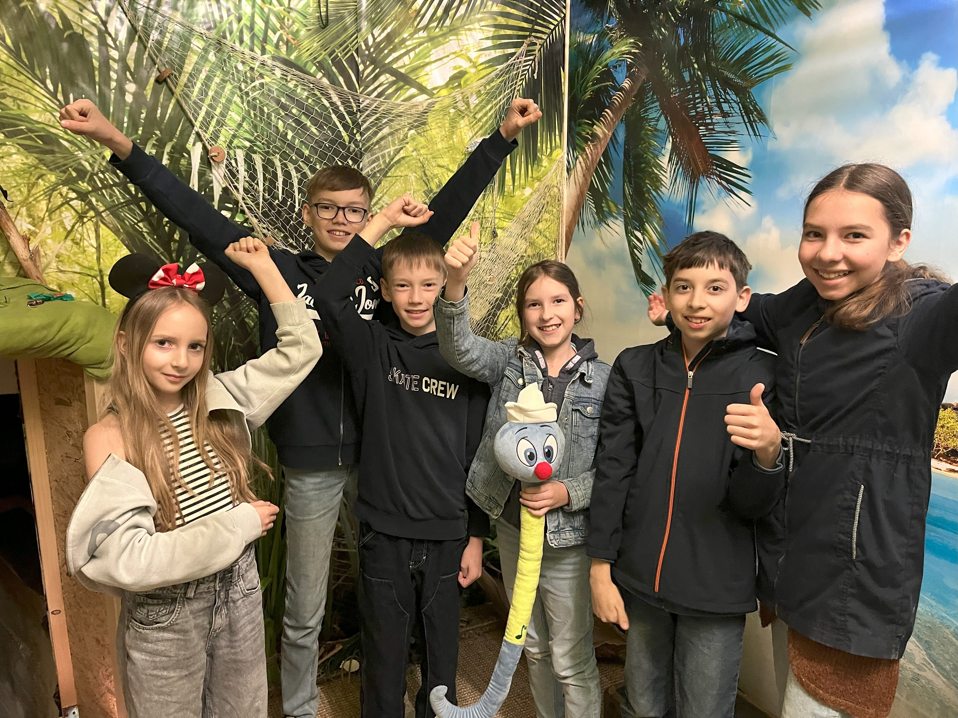 6 children in front of a jungle picture are happy that the puzzle has been solved