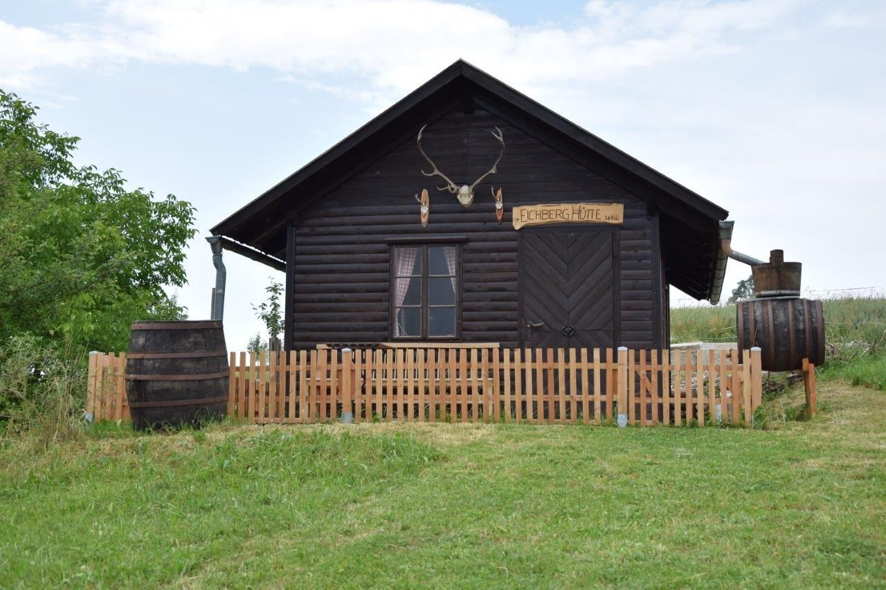 A rustic wooden hut with antlers above the door and a wooden fence in front of it.