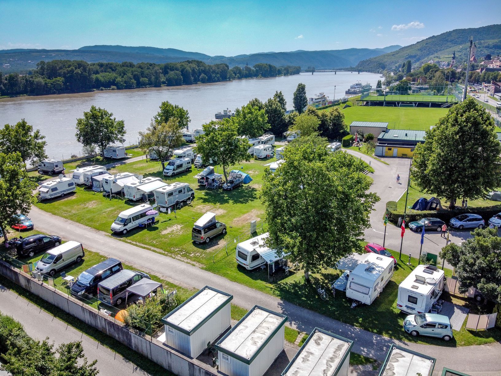 Aerial view of a campsite by the river with mobile homes and tents.