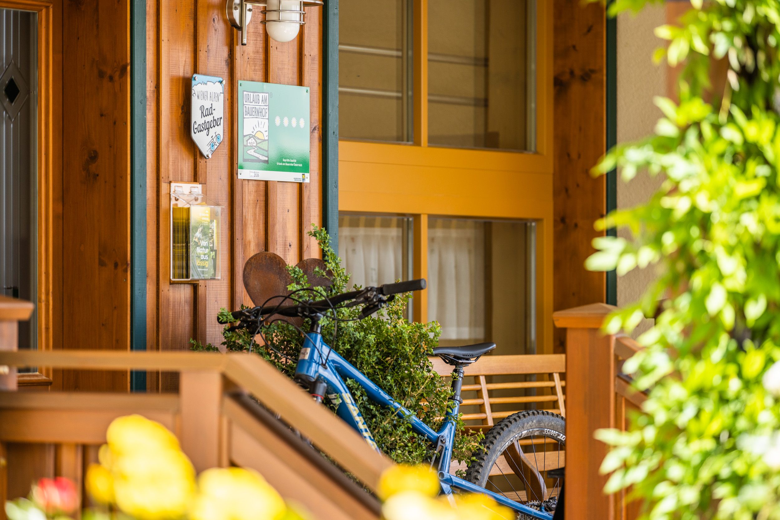 Entrance area of a building with wooden cladding, bicycle and signs.