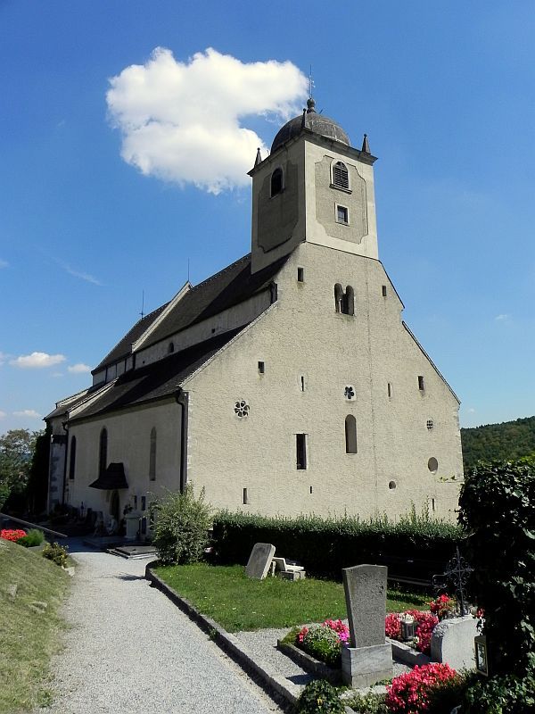 A historic church with a tower and surrounding cemetery under a clear sky.