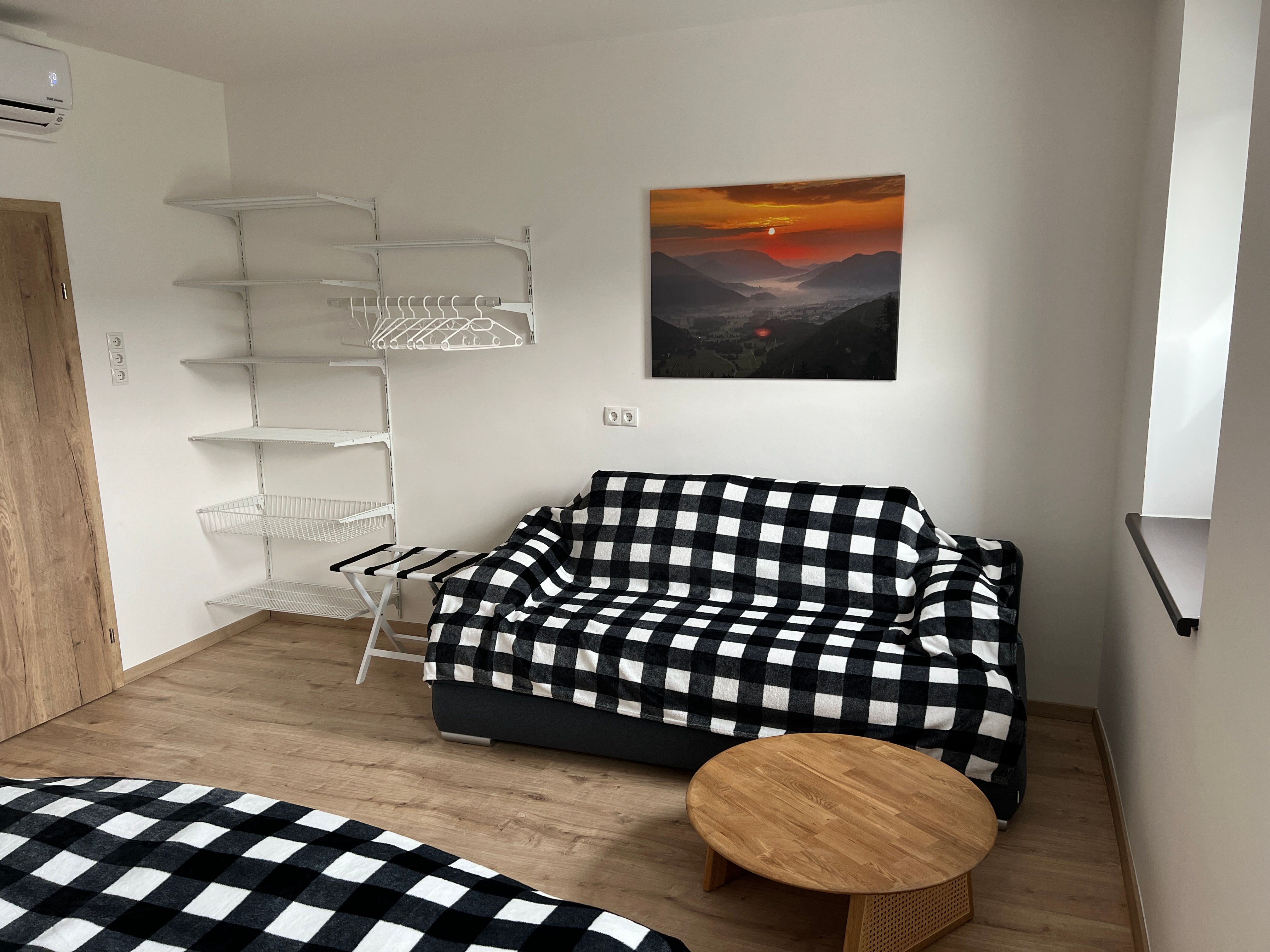 Bedroom with checkered sofa, wall shelf and landscape painting.