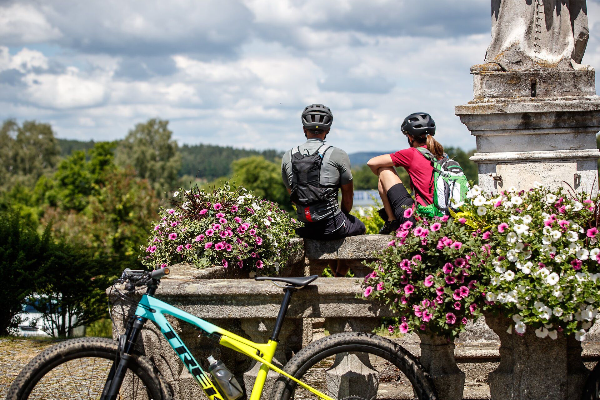 Two mountain bikers enjoy a well-deserved break in the midst of a blossoming landscape. Surrounded by colorful flowers and the fresh mountain air, this place offers the perfect backdrop for adventures in nature.