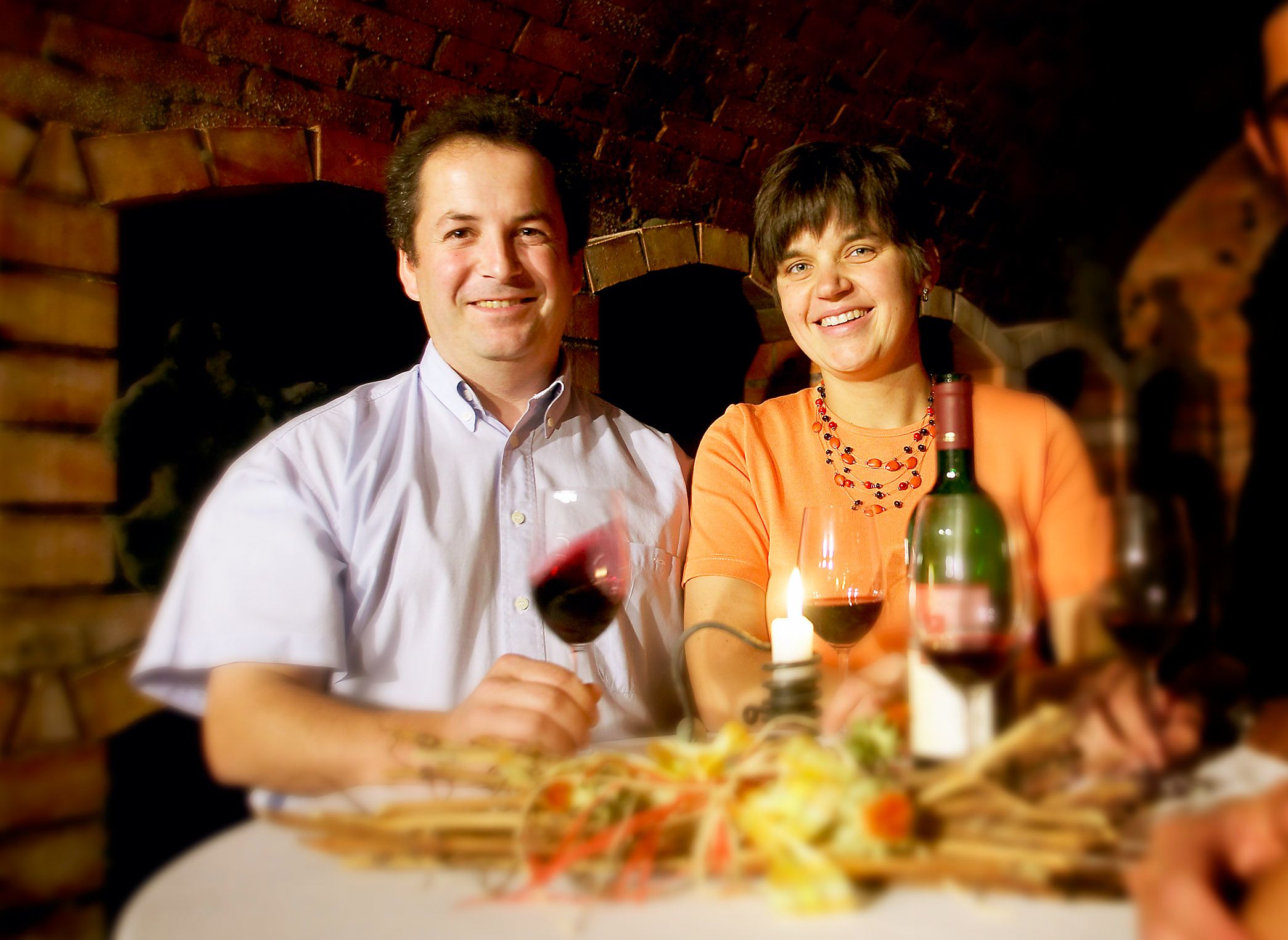 A man and a woman are sitting at a table with wine and a candle.