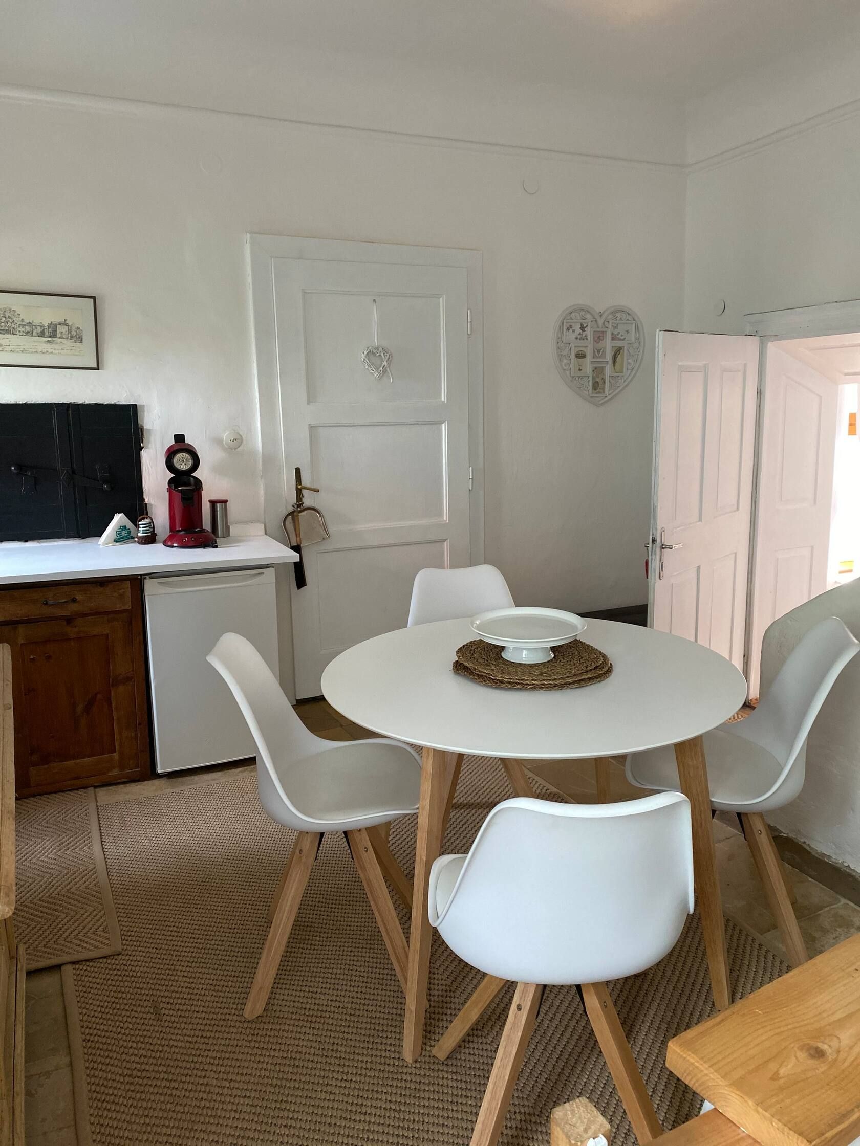 Kitchen seating area with round table and four white chairs on a carpet.